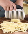 Stainless steel large crinkle cutter with black handle slicing potatoes into wavy fries.