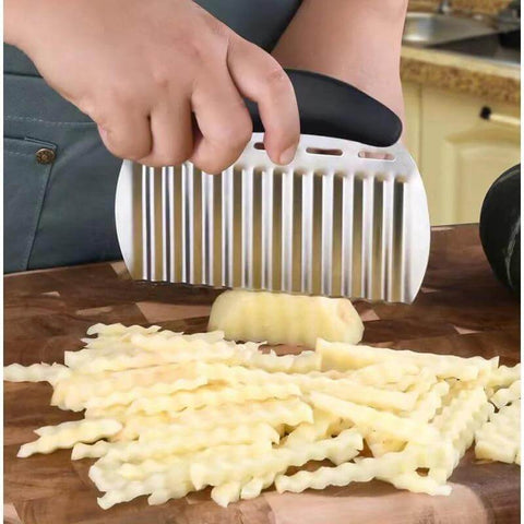Stainless steel large crinkle cutter with black handle slicing potatoes into wavy fries.