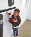 Child holding a red lantern next to a FastTrack Garage Wall Mounted Storage Kit with hooks and rails in a workshop.