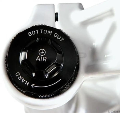 Close-up of a bike suspension air control knob on a white component, showing adjustment for bottom-out and hardness.