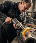 Man using Heavy Duty Four Inch Cotton Buffing Wheels With Half Inch Arbor For Knockout Polishing on metal in workshop.