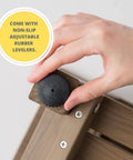 Adjusting non-slip rubber leveler on waterproof shower bench with storage shelf, 18-inch corner seat, heavy-duty HDPE wood-look frame.
