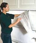 Woman installing Kickass Reflective Foam Core Insulation Roll With Radiant Barrier And Vapor Block on a garage door.