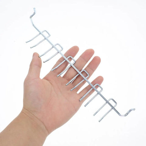 Hand holding metal Two Pack Adjustable Iron Storage Hooks Heavy Duty Pegboard Tool Hangers for Garage Workshop Home Office Organization.