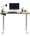 Electric Standing Desk with Solid Steel Frame And Smooth Height Adjustment For Home Office Gaming Setup That Rocks A Sleak Oak Finish, workspace view with monitor and accessories.