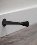10 Pack Stainless Steel Cast Door Stops 3 Inch Matte Black Finish With White Rubber Stopper wall mounted close-up view