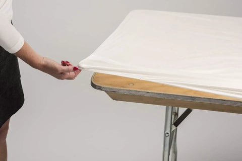 Person adjusting Five Pack Black 6 Foot Plastic Table Covers 30 By 72 Inches to fit banquet tables with elastic corners