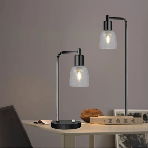 Table lamps with clear seeded glass shades on a desk featuring modern design, displaying focused light effect.