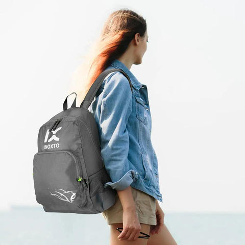 Woman wearing 20L Lightweight Hiking Daypack For Outdoors Foldable Travel Backpack on a hike by the sea, gray color