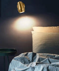 Top Tier Brass Wall Sconce With G4 Socket, modern bedside light illuminating a cozy bedroom setup with decorative pillows.