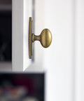 Badass Hella Smooth Antique Brass Cabinet Knobs With Oval Backplate For Kitchen Drawers And Furniture Upgrades Zinc Alloy Hardware Top Shelf Premium Set Of Twelve, close-up view on white cabinet.