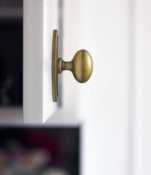 Badass Hella Smooth Antique Brass Cabinet Knobs With Oval Backplate For Kitchen Drawers And Furniture Upgrades Zinc Alloy Hardware Top Shelf Premium Set Of Twelve, close-up view on white cabinet.