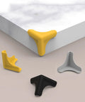 Silicone Corner Guards For Furniture And Home Appliances, Impact Resistant Edge Guards in yellow, black, and gray on a table.