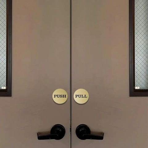 Two Inch Round Push Pull Door Signs Brushed Gold Set Of Two Durable Plastic With Strong Adhesive Foam Tape For Super Easy Install And Clear Legible Messaging In Offices Homes Or Commercial Doors. on double doors