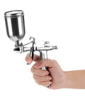 Slick Pro Grade Mini Pneumatic Paint Sprayer With Tough Stainless Steel 0.5mm Nozzle and Wear Resistant Copper Atomizer Cup in hand.