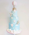 Blue cake decorated with hot air balloon and cloud designs using 13 Piece Hot Air Balloon and Cloud Fondant Cutter Set for Cakes.