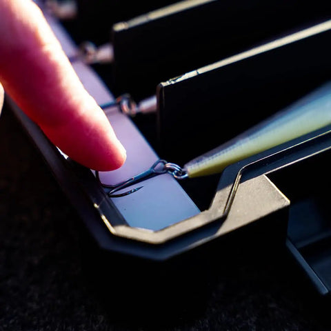 Close-up of a finger touching a hook inside BallistiX Twitch Tackle Tray For Jerkbaits And Topwaters Waterproof Lure Box with a lure visible.