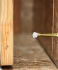 3-Inch Stainless Steel Door Stops With White Rubber Cushion mounted on wall, polished brass finish, prevents door impact.