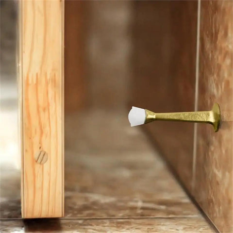3-Inch Stainless Steel Door Stops With White Rubber Cushion mounted on wall, polished brass finish, prevents door impact.