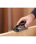 Person using hand planer for woodworking with adjustable depth cutter and 21 degree angle, cast iron base, smooth cross grain planing.