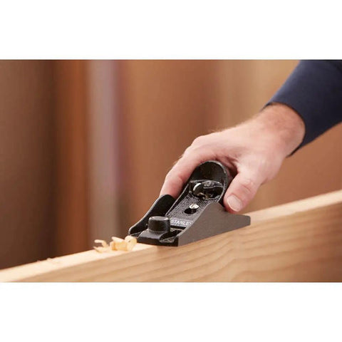 Person using hand planer for woodworking with adjustable depth cutter and 21 degree angle, cast iron base, smooth cross grain planing.