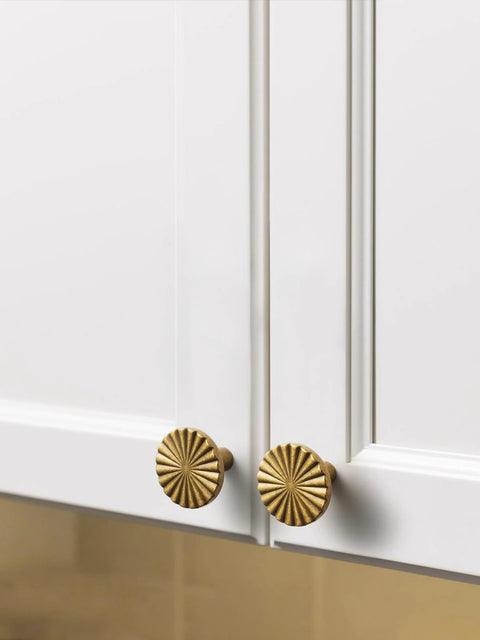 Antique Brass Cabinet Knobs 10 Pack Vintage Flat Drawer Pulls installed on white kitchen cupboard doors.
