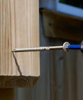 Close-up of a 50 Pack 5/16 Inch X 4 Inch T40 Star Drive Structural Screw for Decking being installed into wood.