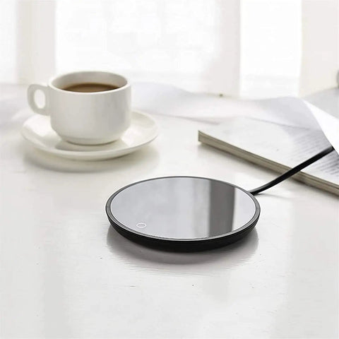 Top Shelf Electric Mug Warmer With Automatic Shut Off Keeps Your Coffee Tea And Water Nice And Toasty On Desk Or Nightstand Snug Little Heater in glossy black next to a cup.
