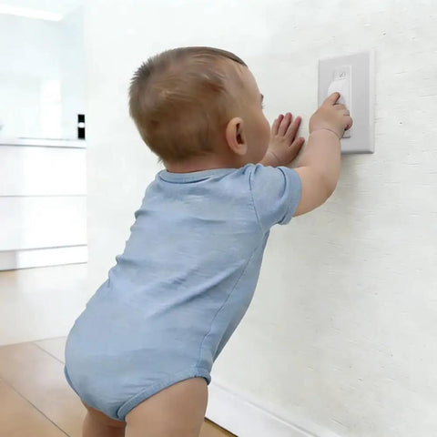 Child reaching for childproof light switch plate cover with safe home shield to stop little ones from flipping the switch.