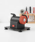 Solid Compact Corded Electric Bench Grinder Tool Polisher Cutter With Dual Wheel Setup, black casing and red wheel on workbench.