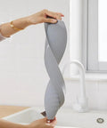 Hand holding Silicone Sink Splash Guard Keeps Mess In Check, Sink Flaps Heighten Countertop Edges, Durable Dark Gray Kitchen Accessory