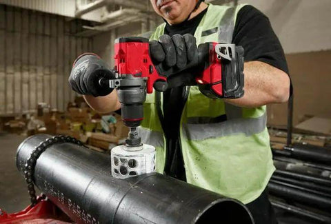 Worker using Badass 18V 1/2-Inch Compact Cordless Drill Driver Bit Socket Adapter on metal pipe in job site.