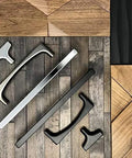 Variety of Top Knobs Riverside Pulls in different finishes on wood background, focusing on contemporary bar handles for kitchen and bath furniture.