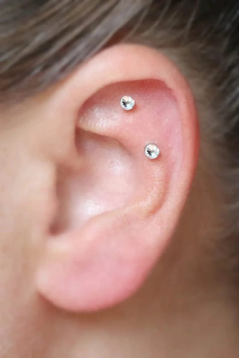Close-up of ear with two cartilage piercings using threadless stud jewelry from Threadless Piercing Tapers Set Go To For Changing And Insertion Tools 16G 18G 20G Titanium Threadless Insertion Pins Includes 3 Pcs Piercing Tapers And Change Tool Flat Back Earring Applicator For Most Threadless Stud Jewelry.