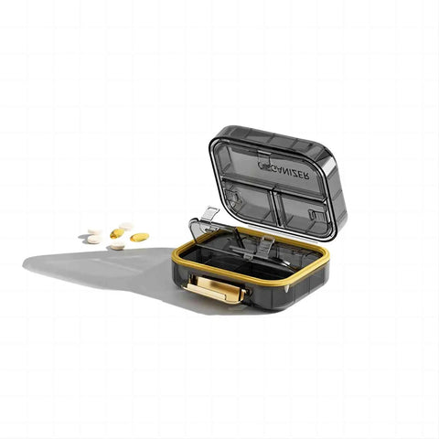 Small black and yellow portable pill organizer open with compartments, visible pills nearby on white background.