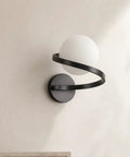 MAHGNTKCX Black Wall Sconce with Opal Glass Globe and Spiral Metal Frame showcasing the sculptural spiral design.