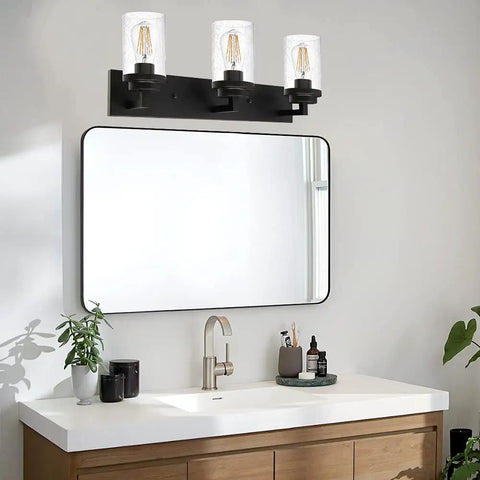 Bathroom scene with a Three Light Matte Black Vanity Light With Seeded Glass Shades above a sink and mirror setup.