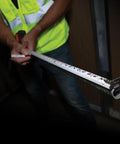 Person using Heavy-Duty Tape Measure With Nylon-Coated Blade, 25-Foot Reach, Double-Hook, Double-Sided Measurements in dim setting