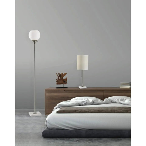 Fiona Torchiere Floor Lamp In Brushed Steel With Marble Base And Opal Glass Shade beside bed in modern bedroom.