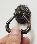 Person holding dark antique brass ring pull for dresser drawers and cabinets, vintage swing bail handle, zinc alloy, 1.9 inch diameter.