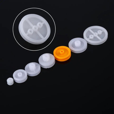 Seven Piece Dope Plastic Pulley Kit For DIY Belts And Model Making, 2A 2B Shaft Fit, white and orange plastic pulleys on black background