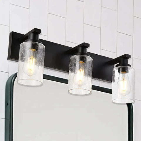 Three Light Vanity Bathroom Light Fixture Over Mirror Black Finish With Cylinder Seeded Glass Shades For A Sleek Dope Look