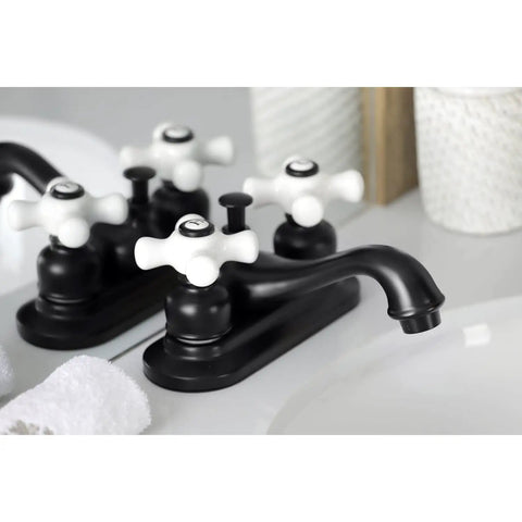 Black lavatory faucet with porcelain cross handles on a bathroom countertop reflective surface.