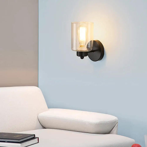 One Light Matte Black Bathroom Vanity Sconce With Clear Glass Shade Vintage Style Wall Light Fixture illuminated on wall