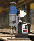 Heavy Duty Reversible Magnetic Drill With Rock Solid Grip And 10.5 Amp Motor crushing steel with drill bit in industrial setting.