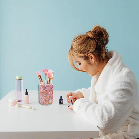 Woman applying nail polish at desk with Glitter Pink Desk Pen Holder And Makeup Brush Organizer Cup in the background