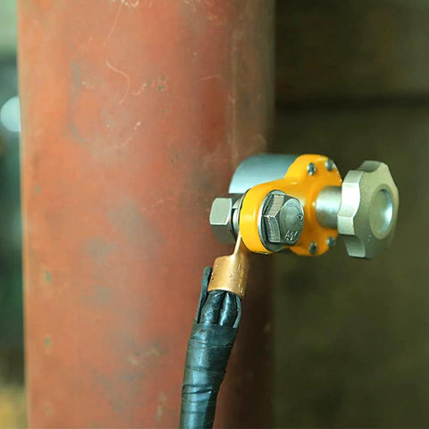 600A magnetic welding ground clamp mounted on a metal pipe; yellow body with silver bolts and black welding cable