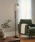 Tall Industrial LED Floor Lamp With Adjustable Head And Rustic Glass Teardrop Shade, Black Finish beside green sofa