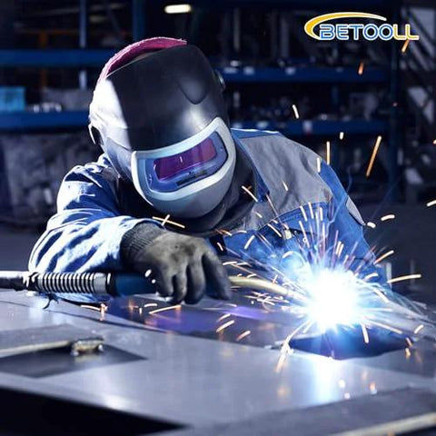 Front view of a welder in protective helmet welding metal; sparks fly and BETOOLL logo is visible.