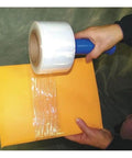Top Shelf Heavy Duty Hand Stretch Wrap Clear Cast Roll Pack Of Four, 3 Inch Wide By 600 Feet Long, 150 Gauge With Reusable Handle, No Sweat Stretching Made In Usa, applying wrap on envelope.